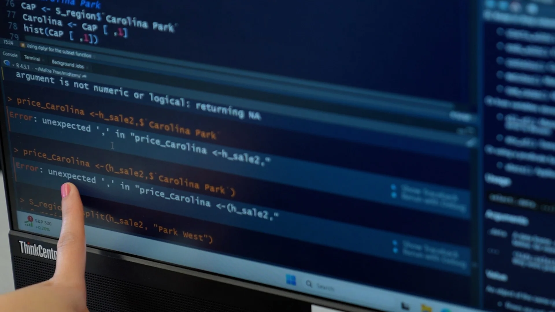 Person pointing at a computer screen displaying data science code with error messages highlighted in a programming editor.