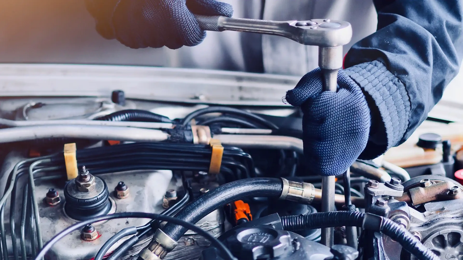 Photo of gloved hands using socket wrench on an engine