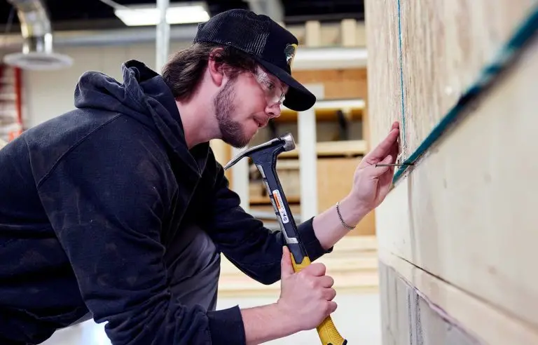 Student hammering a nail in carpentry class.