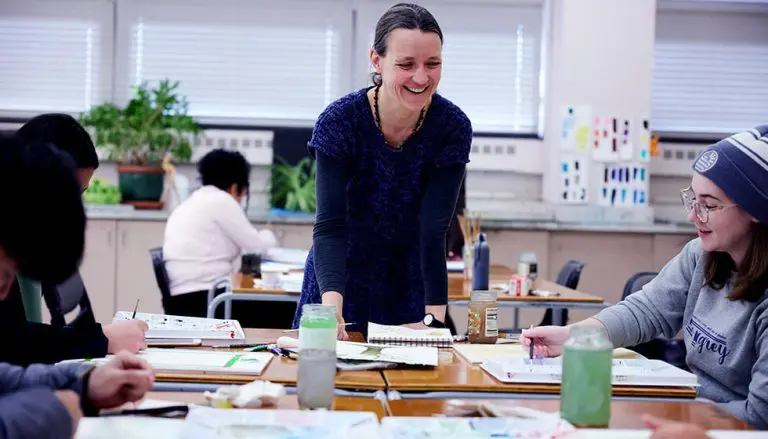 Teacher interacting with students in art class.