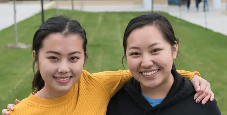 photo of two students on front lawn smiling