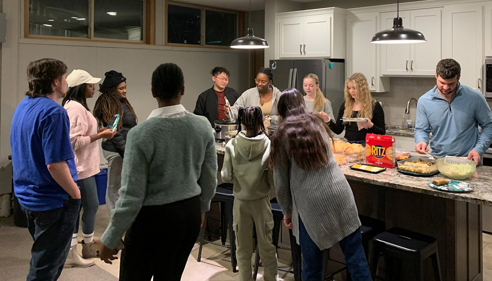 Cru Club students standing around a kitchen island making food