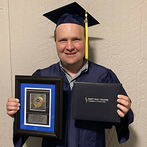 Jonathan Erber in graduation attire holding ASE award and diploma