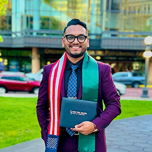 Syed Joy in front of River Center with SPC diploma.