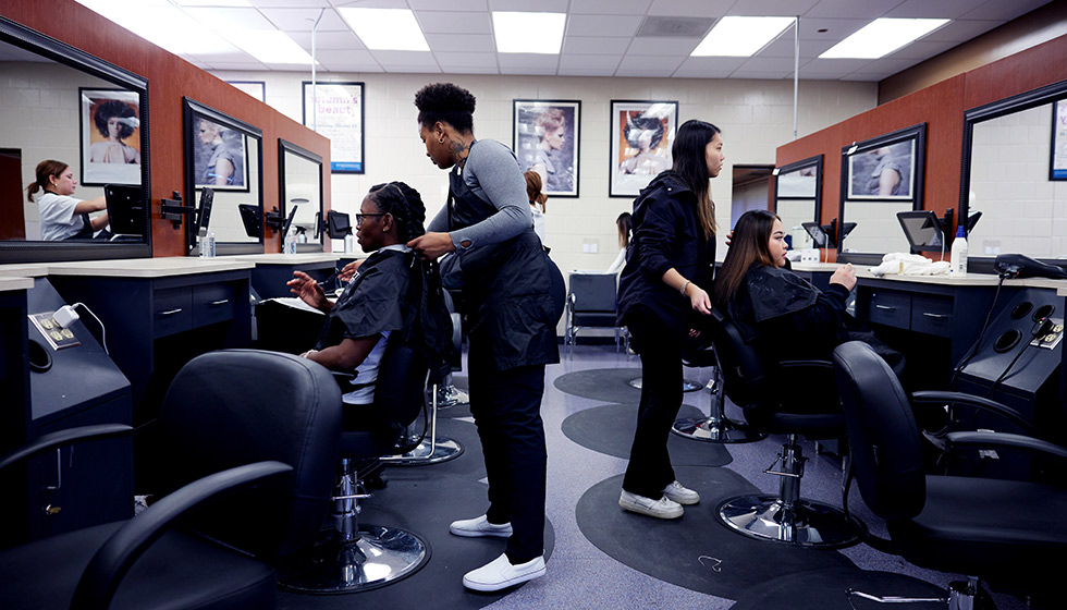 The SPC salon with three stylists attending to clients in chairs. Mirrors reflect their work.