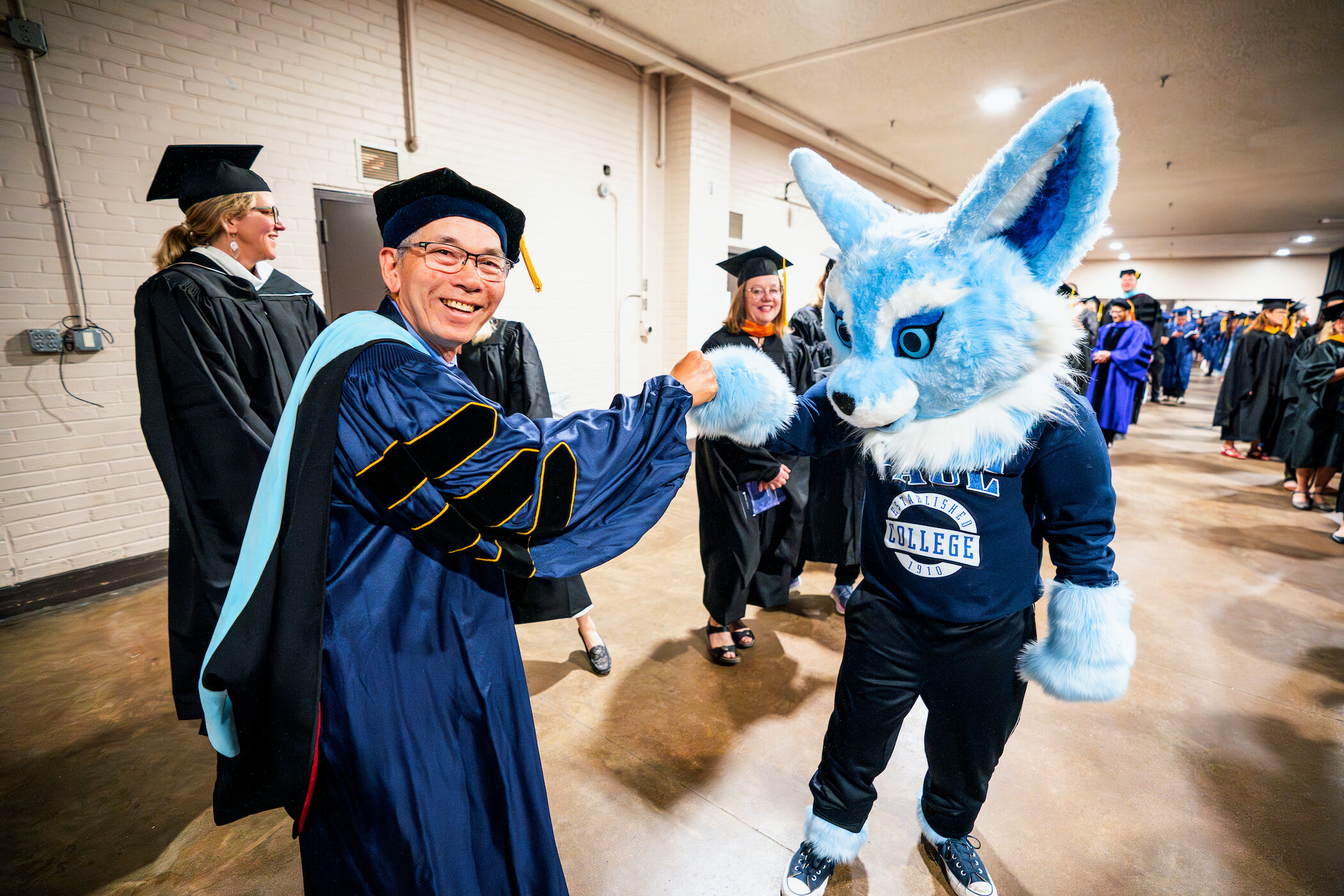 Mascot giving a faculty a high five at graduation