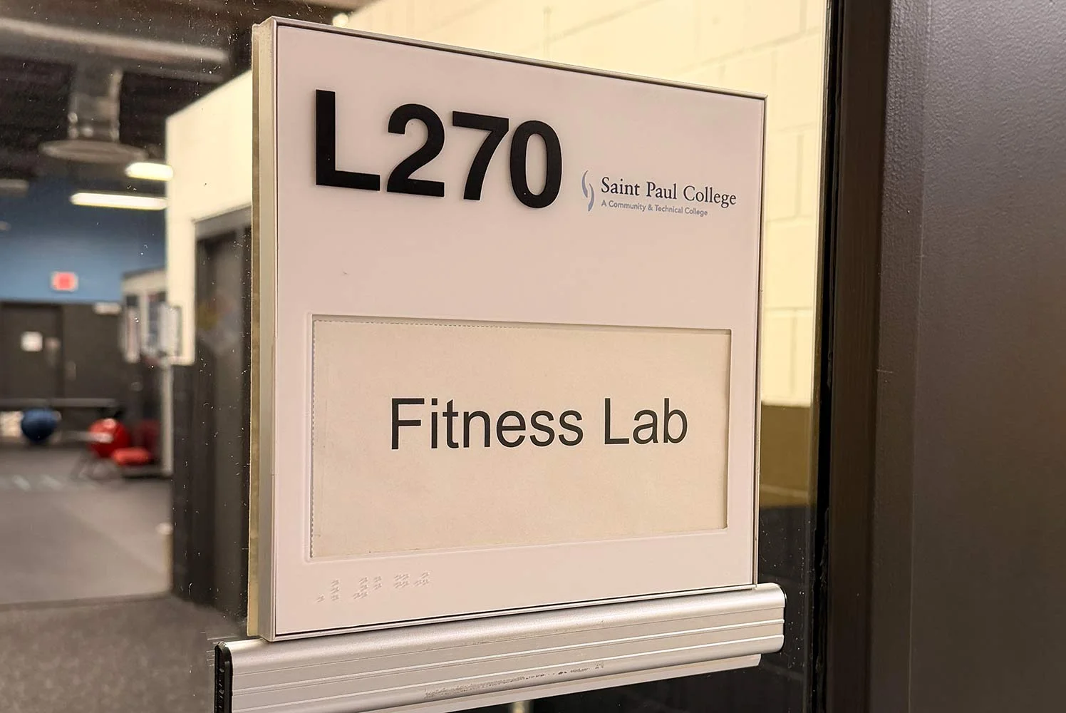 Door sign reading ‘L270 Fitness Lab’ with Saint Paul College’s name and logo.