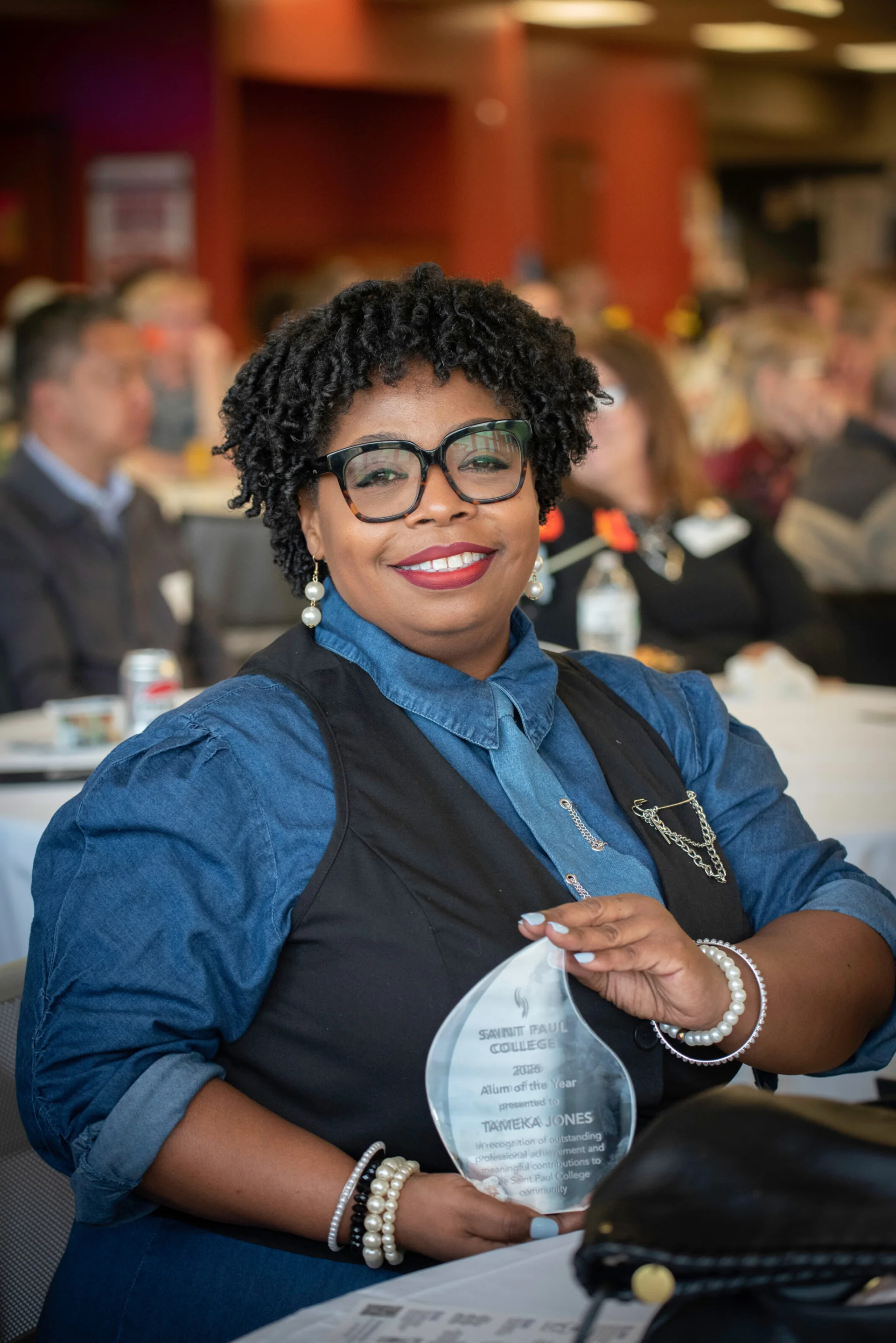 Tameka Jons showing off her award while sitting at a table