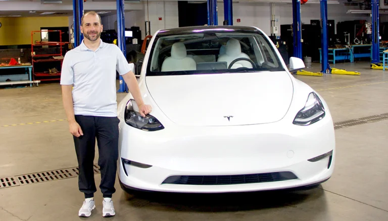 Instructor standing next to Tesla Model Y in EV training lab for hands-on electric vehicle technician training