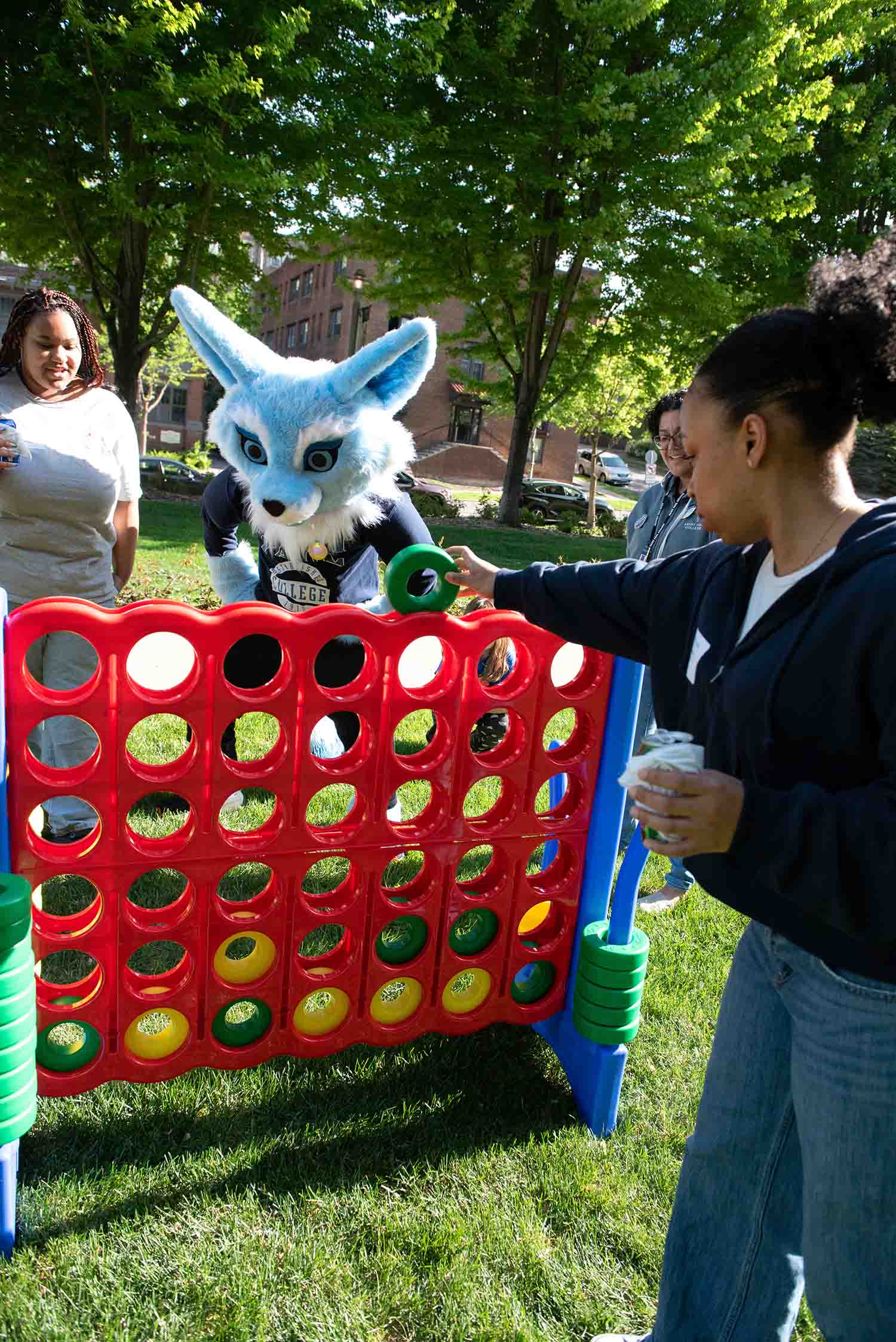 Attendees playing giant Connect Four with Saint Paul College mascot at Friends on the Lawn 2026