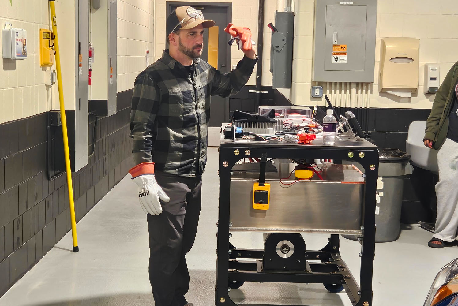 Automotive Instructor, Jake, is standing next to a cart that he is using to share tools and safety gear.