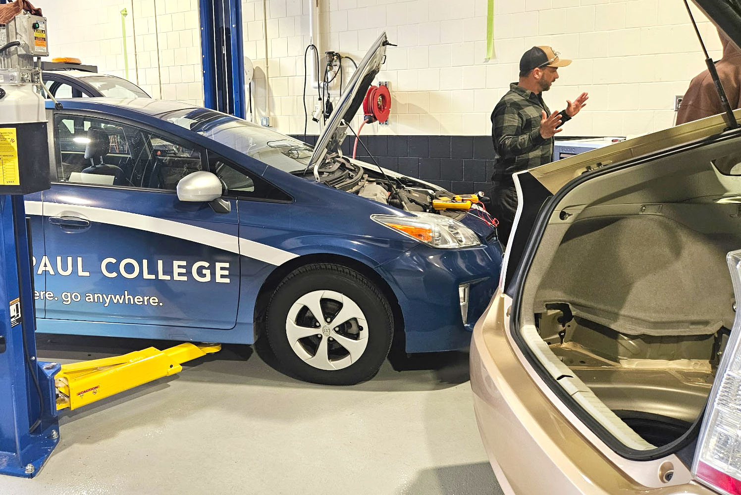 Automotive Instructor, Jake, standing next to Saint Paul College branded hybrid car.