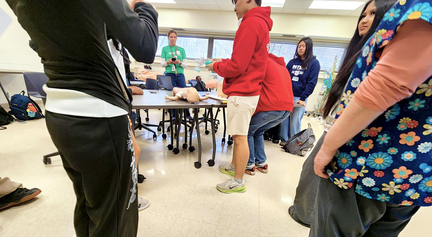 High school students practice hands-on nursing skills with infant mannequin in Saint Paul College healthcare training lab