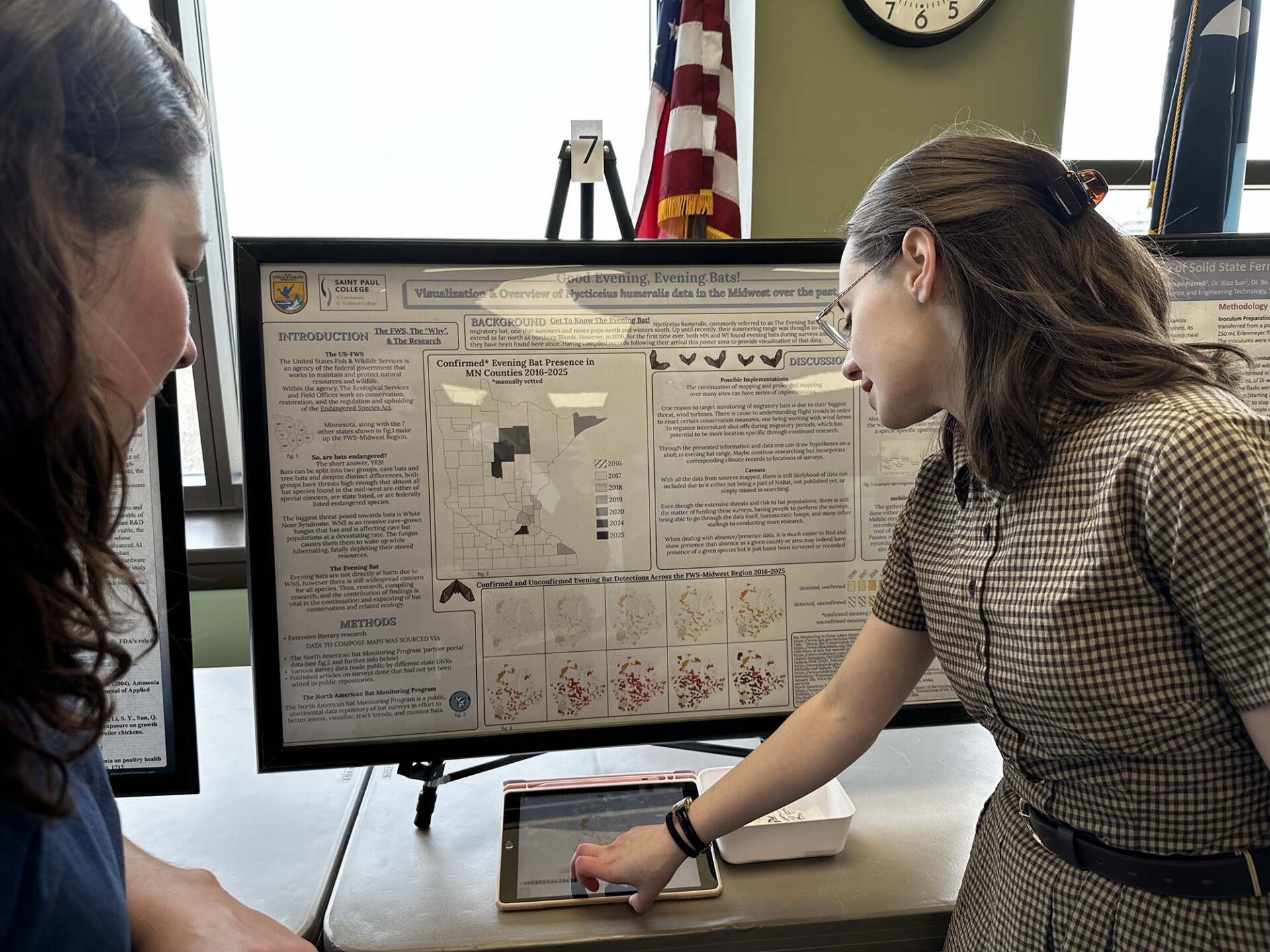 Dede Baltus at Research Showcase explain her project to a woman demonstrating student success.