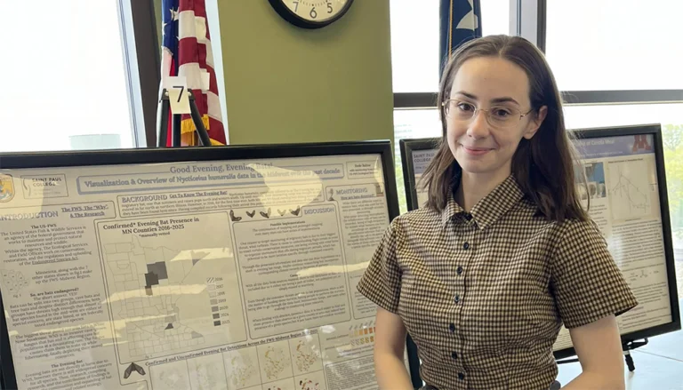 Dede Baltus, a female biology student, standing next to her research on bats