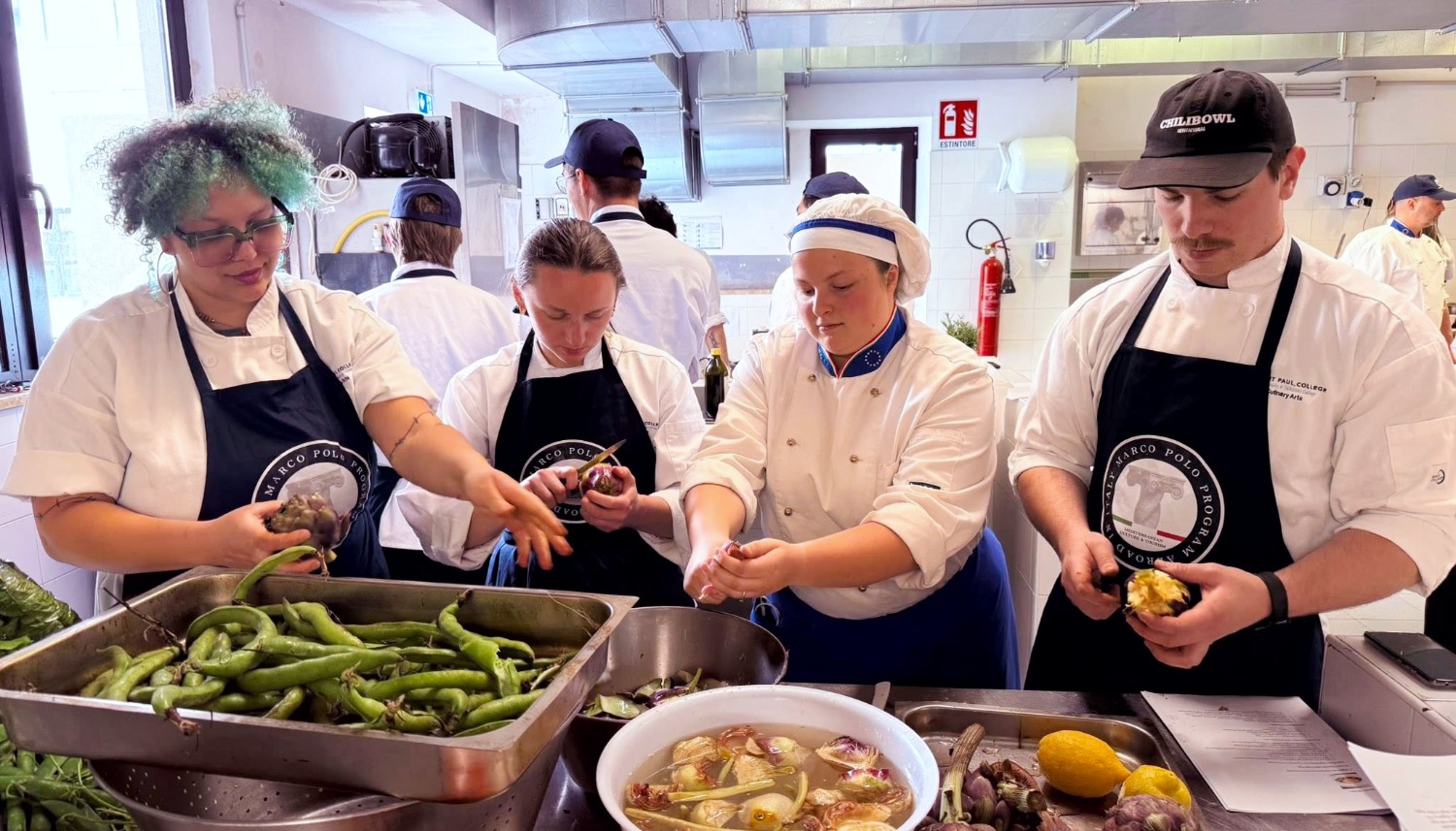 Culinary students hands-on cooking in Italy preparing fresh vegetables in professional kitchen during culinary study abroad program and international training