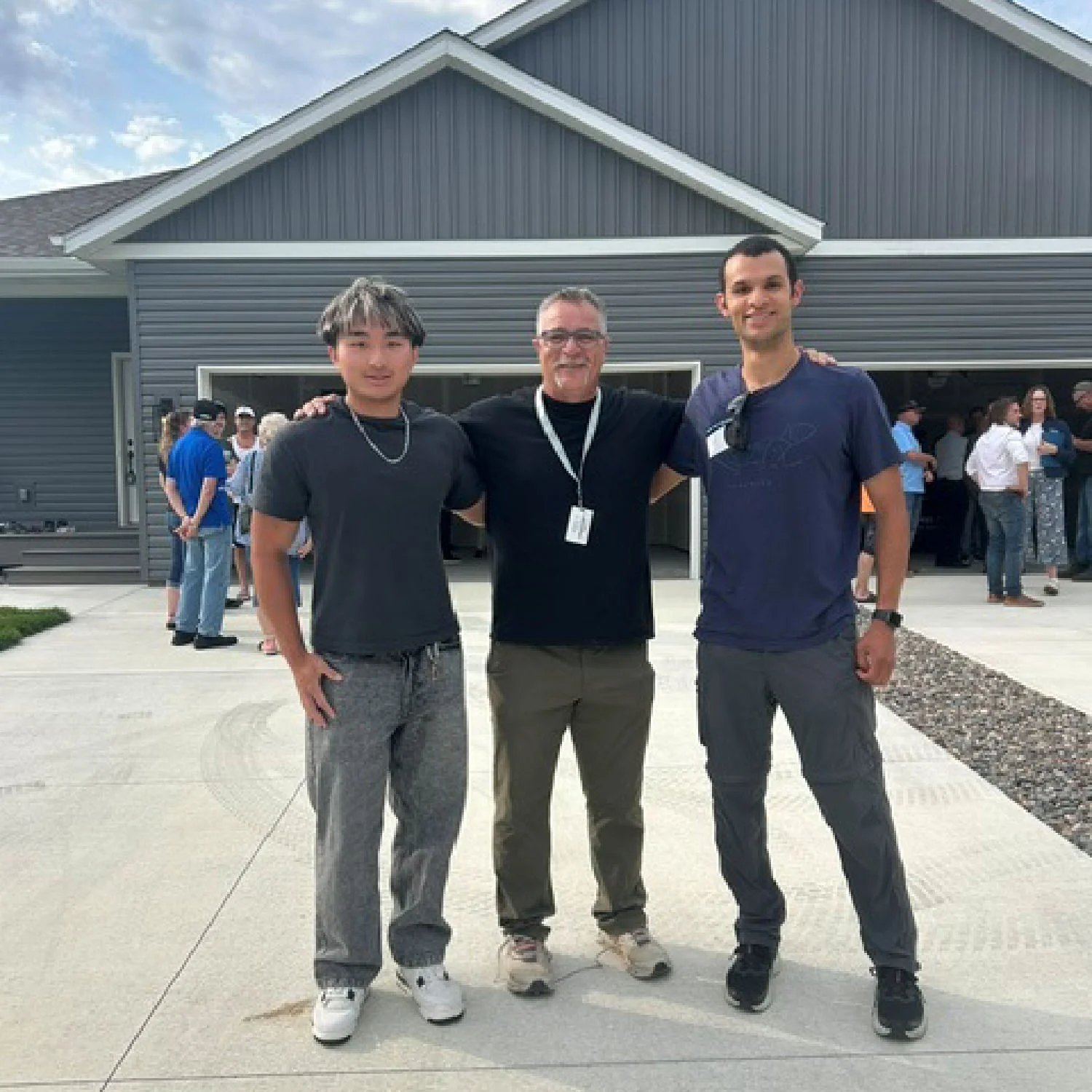 Thomas Leiskau standing on the driveway with two students