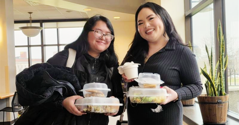 Two students showing off the food they were just served by the Culinary students