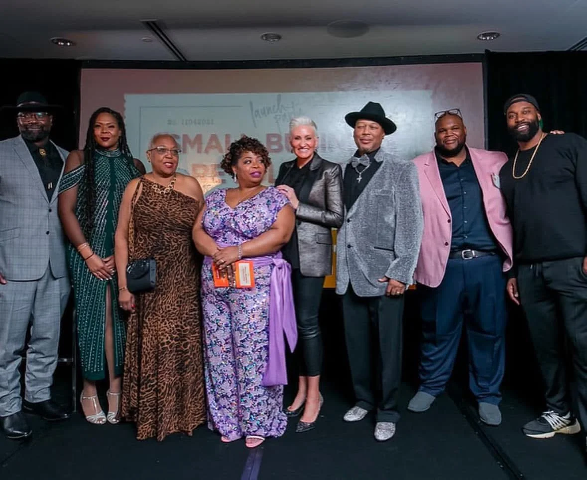 Tameka Jones standing in a group on a stage at a small business event.