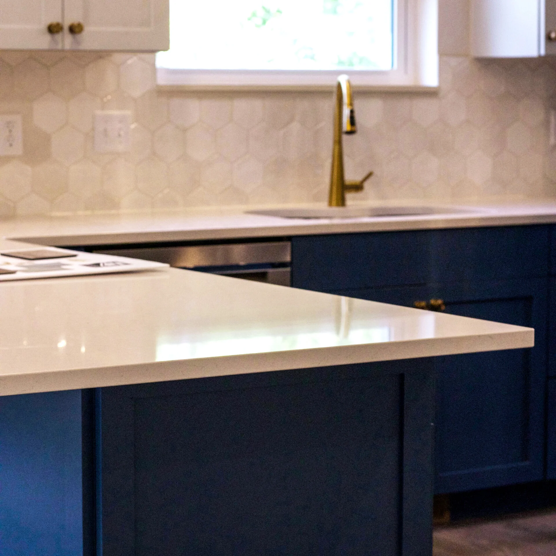 Hexagon tile backsplash and blue lower cabinets in the modern kitchen of one of the units