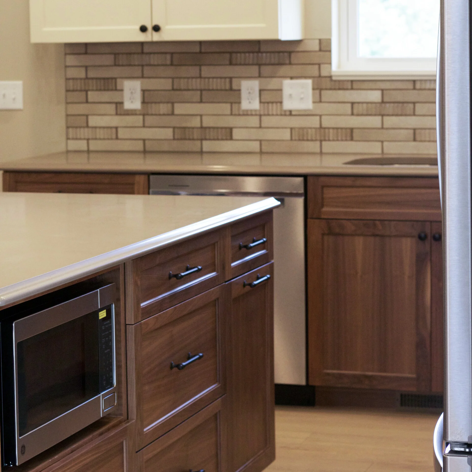 Walnut lower cabinets with horizontal stacked tile backsplash in the more traditional styled unit