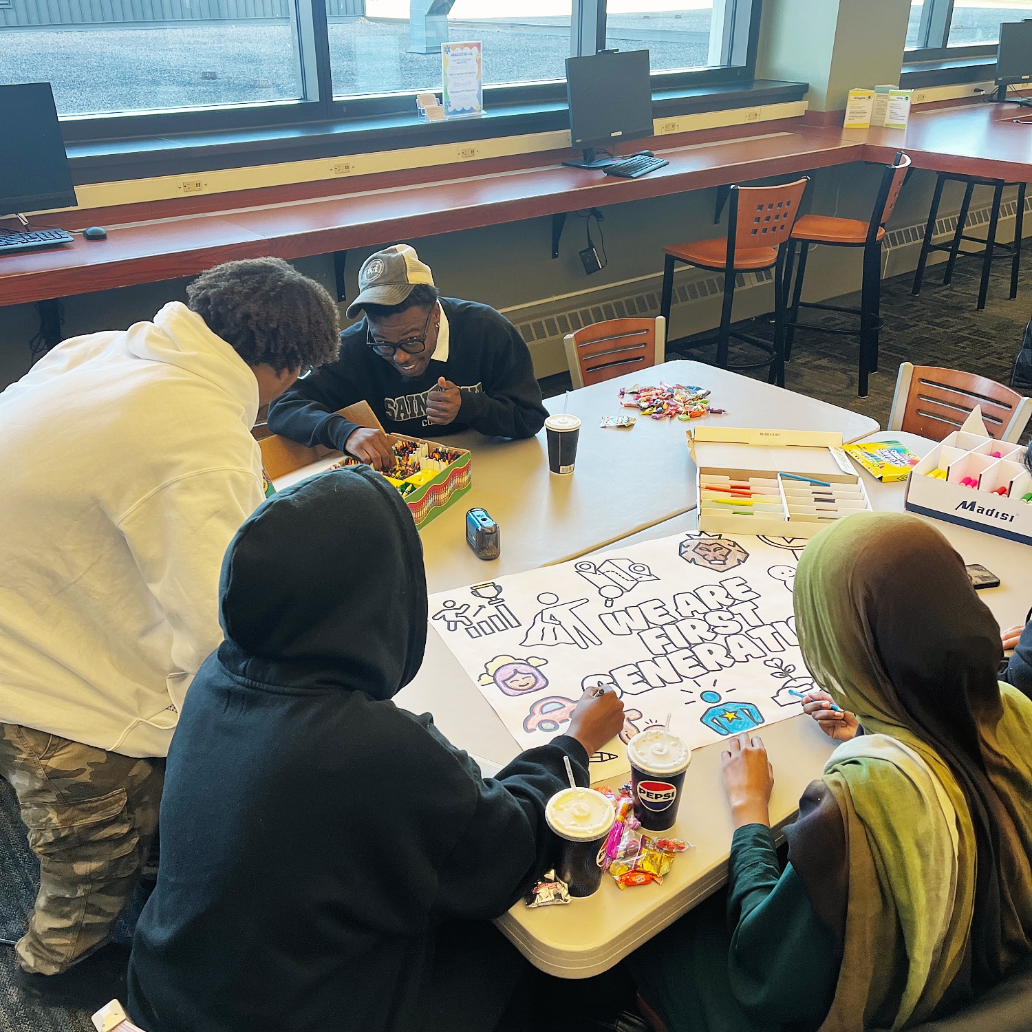 Four student in a meeting space creating posters for first generation people.