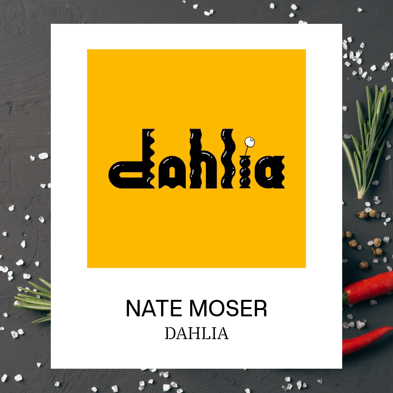 White card displaying the Dahlia logo, featuring stylized black lettering on a bright yellow square. The card is set against a dark textured background with scattered coarse salt, rosemary sprigs, peppercorns, and red chili peppers. Text below the logo reads “NATE MOSER” and “DAHLIA.”