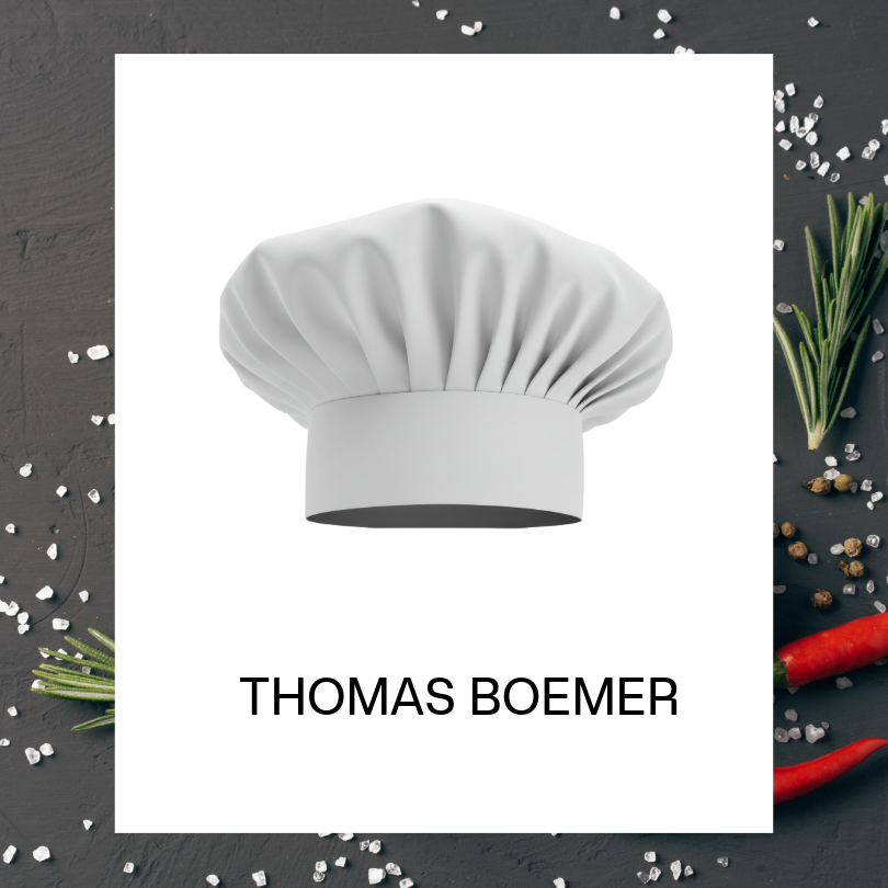 White chef's hat illustration centered on a white card against a dark food-themed background decorated with coarse salt, rosemary sprigs, peppercorns, and red chili peppers. The name "THOMAS BOEMER" appears below the chef's hat.