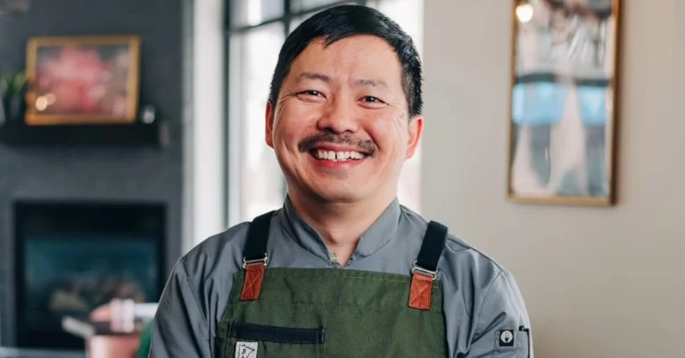 Kou Cha smiling in the dining area of Pink Ivy Kitchen & Bar